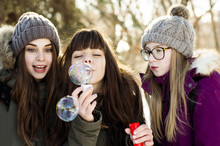 Caucasian Girls Blowing Bubbles Outdoors In Winter