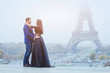 happy couple traveling in Paris, smiling man and woman posing in fancy fashion clothes on Eiffel Tower background during their honeymoon