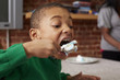 © Granger Wootz/Blend Images - Black boy eating cake at table