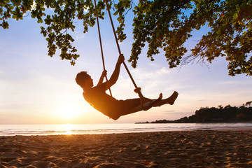 Wall Mural - swing on paradise tropical beach at sunset, happy people enjoying summer