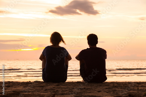 Fotografía friends sitting together on the beach and watching sunset, friendship concept