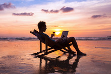 Silhouette Of Successful Business Man Reading Emails On Laptop On The Beach At Sunset, Freelance Job Concept, Work Abroad