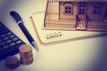 Concept Of Housing Purchase And Insurance. Office Desk Table With Supplies Top View. Calculator. Golden Coins, Pen, Notepad, Green Model House, Wooden Block Word 