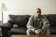 © Roberto Westbrook/Blend Images - Mixed race soldier sitting on living room sofa