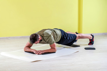 Young man at gym, exercising with friction pads.