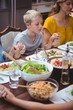 © WavebreakMediaMicro - Family holding hands while praying at dining table