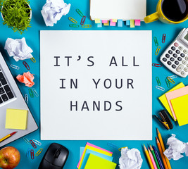 it's all in your hands. office table desk with supplies, white blank note pad, cup, pen, pc, crumple
