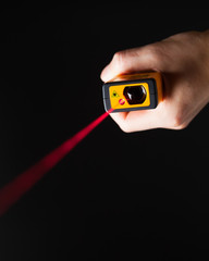 laser distance meter in hand, black background