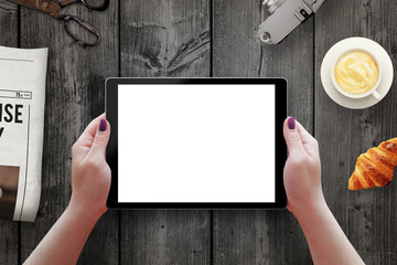Poster - Tablet with isolated screen in woman hands. Morning time with newspaper, croissant, coffee on table.