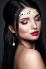 Beautiful woman portrait. Young lady posing close up on dark background. Brunette girl with gorgeous make up and hairstyle. Dark Pink lipstick. Jewelry on head. Nice earrings