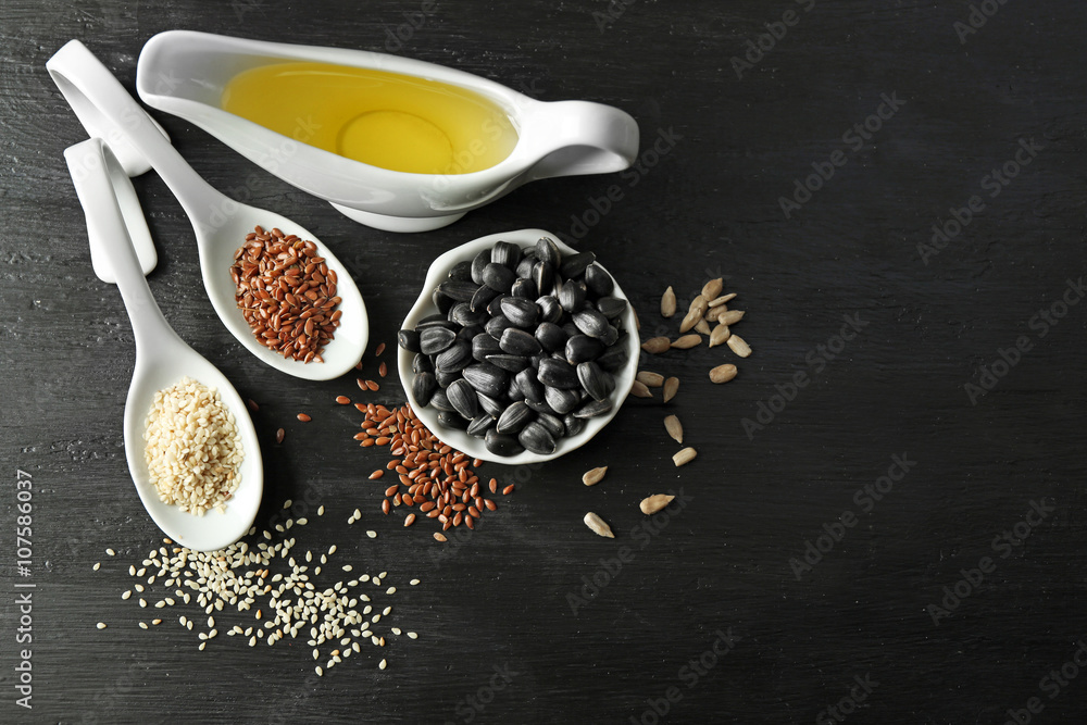 Different kinds of seeds and oil on wooden table