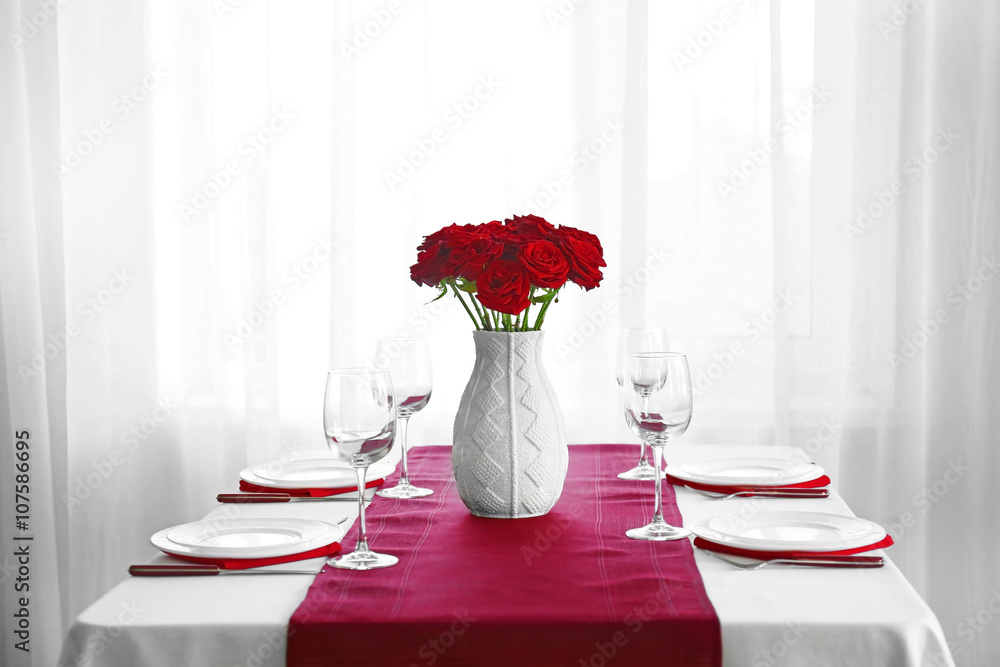 Vase with red roses on a holiday served table