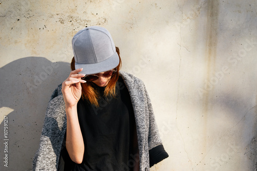 Fotografia Female model wearing a black blank cap and sunglasses looking away