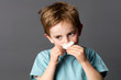 healthcare learning - sick young kid with red hair and freckles using a tissue after a cold, rhinitis or spring allergies, grey background studio