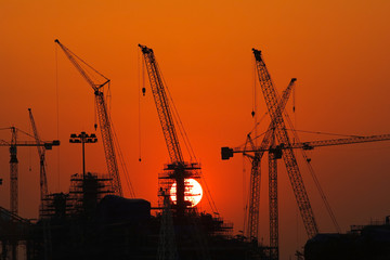 Wall Mural - Industrial landscape with silhouettes of cranes on the sunset background