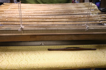 Canvas Print - Close up of gold silk weaving on loom