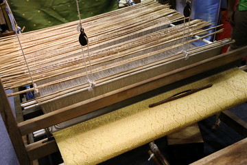 Canvas Print - Close up of gold silk weaving on loom