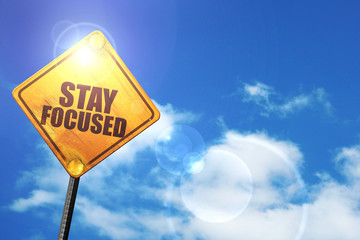 Yellow road sign with a blue sky and white clouds: stay focused