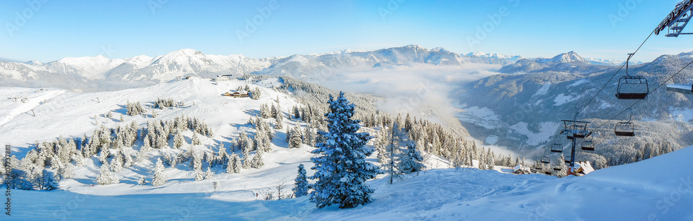 Alpine ski slope mountain winter panorama with ski lift,skiers and snow covered forest. - obrazy, fototapety, plakaty 