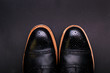 black oxford shoes with shoelace on black background closeup, top view