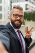 Young happy bearded businessman standing outside office building