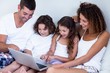 © WavebreakMediaMicro - Family using laptop together on bed