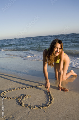 Femme à La Plage Dessinant Un Coeur Sur Le Sable Buy This