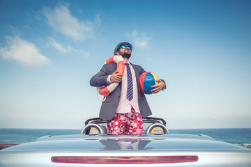 Wall Mural - Businessman standing on a beach near car