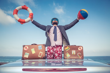 Canvas Print - Businessman standing on a beach near car