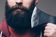 Close up of beard Confident young bearded man carrying a big axe on shoulder and looking at camera while standing against grey background