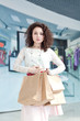 © photo_mts - Happy shopper. Caucasian girl in the mall shopping. Portrait of a girl with shopping bags on the background of shop window.