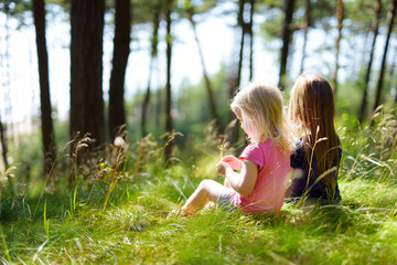 two adorable little sisters hiking in a forest