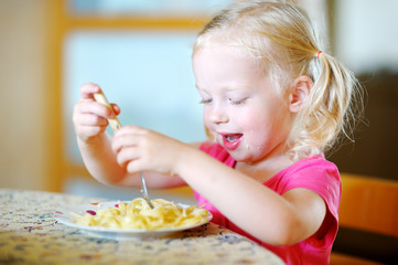 Wall Mural - Cute funny little girl eating spaghetti