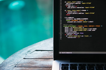 laptop on a wooden table against the background of accepted swimming pool