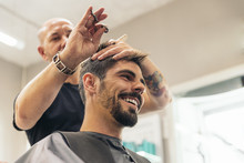Hairstylist Making Men's Haircut To An Attractive Man.