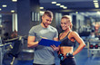 © Syda Productions - smiling young woman with personal trainer in gym