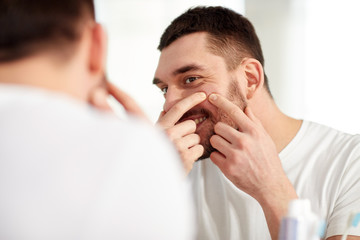 Wall Mural - smiling man squeezing pimple at bathroom mirror