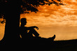 © ZoneCreative - Man silhouette sitting under tree on cloudy day outdoor
