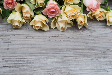 Wall Mural - Pink and yellow roses over wooden background