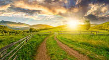 Road And Wooden Fence On Hillside At Sunset