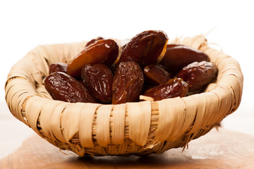 Sweet dried dates fruit in small bowl, mediterranean desert on w