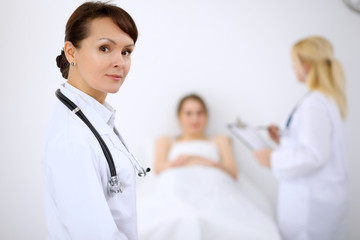 Wall Mural - Female doctor smiling on the background with patient and his doctor