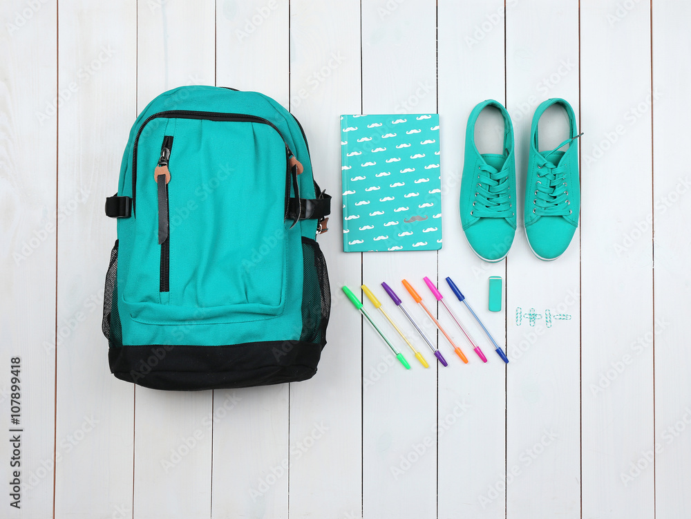Backpack and school supplies on wooden background, close up. Top view.