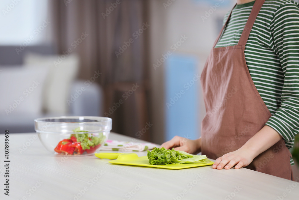 Young woman preparing vegetable salad in the kitchen