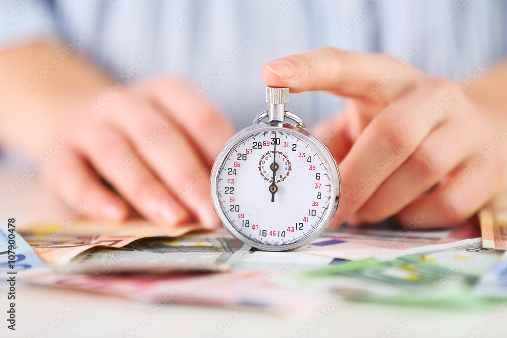 Time is money concept. Stopwatch  on the table with money, close up