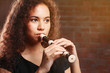 © Africa Studio - Beautiful young woman playing on recorder over brick wall background