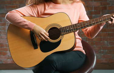 Wall Mural - Beautiful young woman playing on guitar over brick wall background