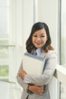 © DragonImages - Portrait of smiling Asian business executive with folders