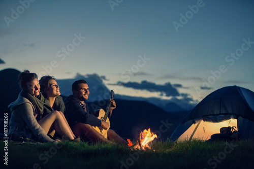 Fotografía Tres amigos de camping con fuego en la montaña al atardecer