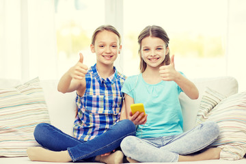 Wall Mural - happy girls with smartphone sitting on sofa